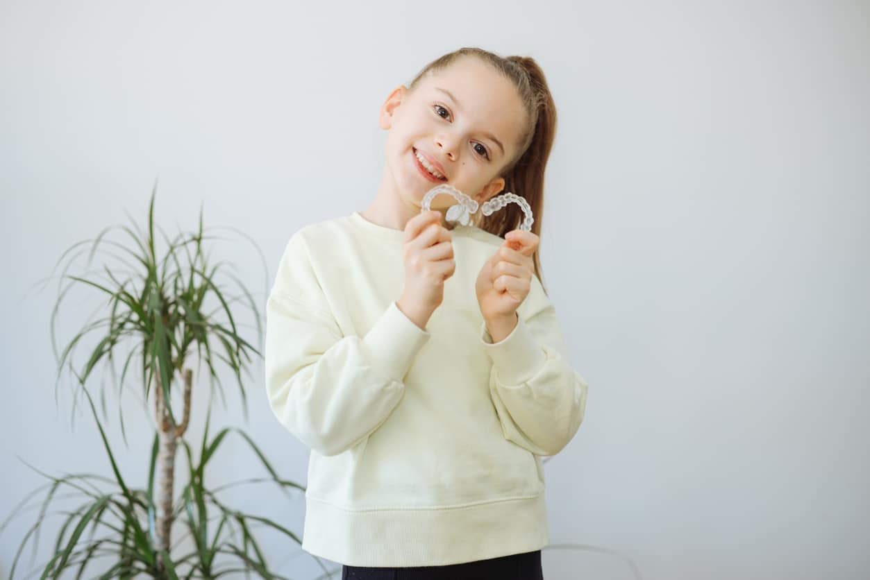 Young smiling girl holding metal braces close-up | Advanced Orthodontics in Burien, WA