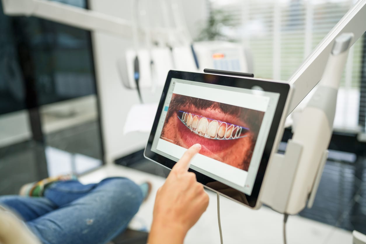 Examining dental images on monitor of patient in the clinic.